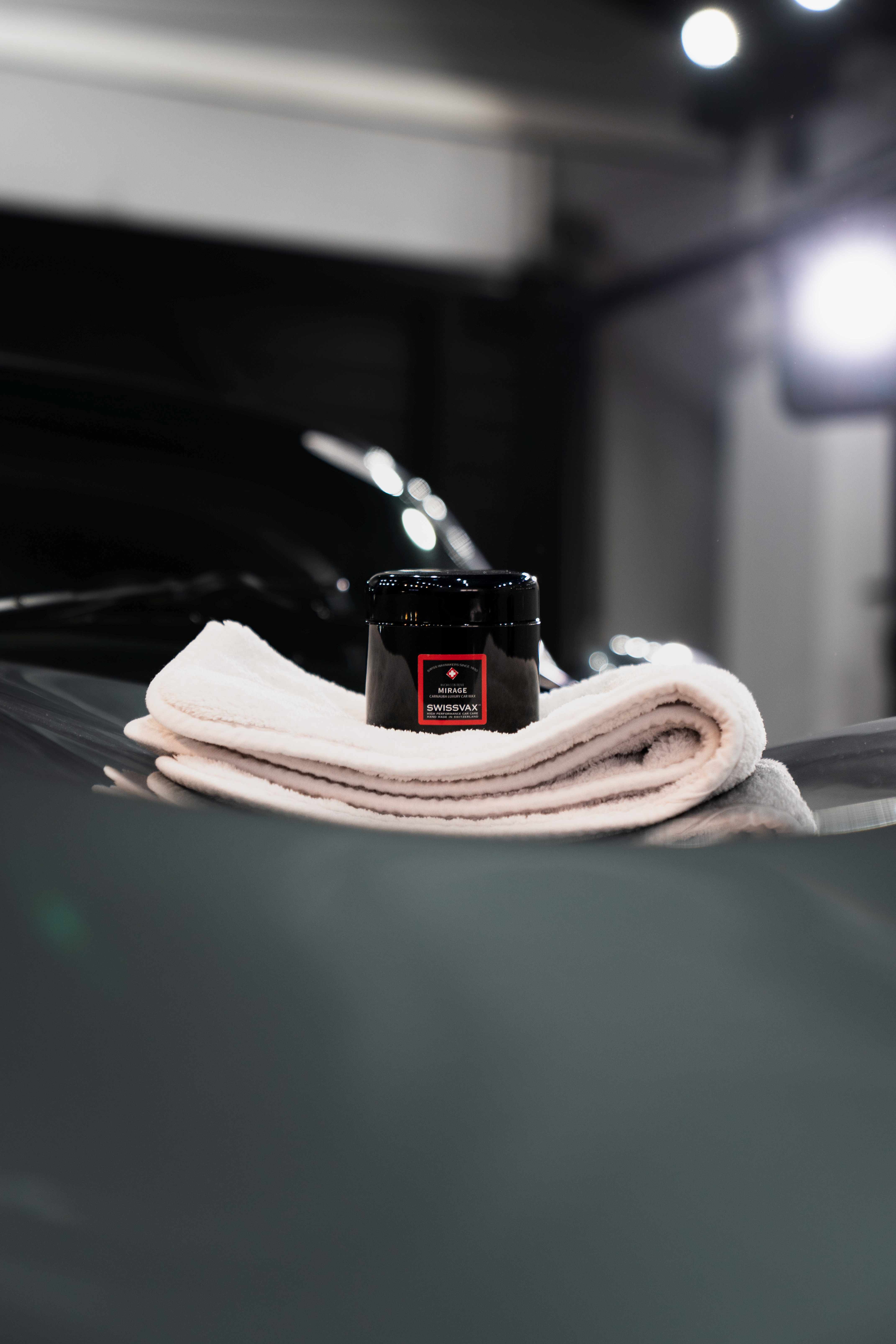 Cire Swissvax Mirage posée sur un microfibre, prête à être appliquée sur la carrosserie d'un véhicule d'exception