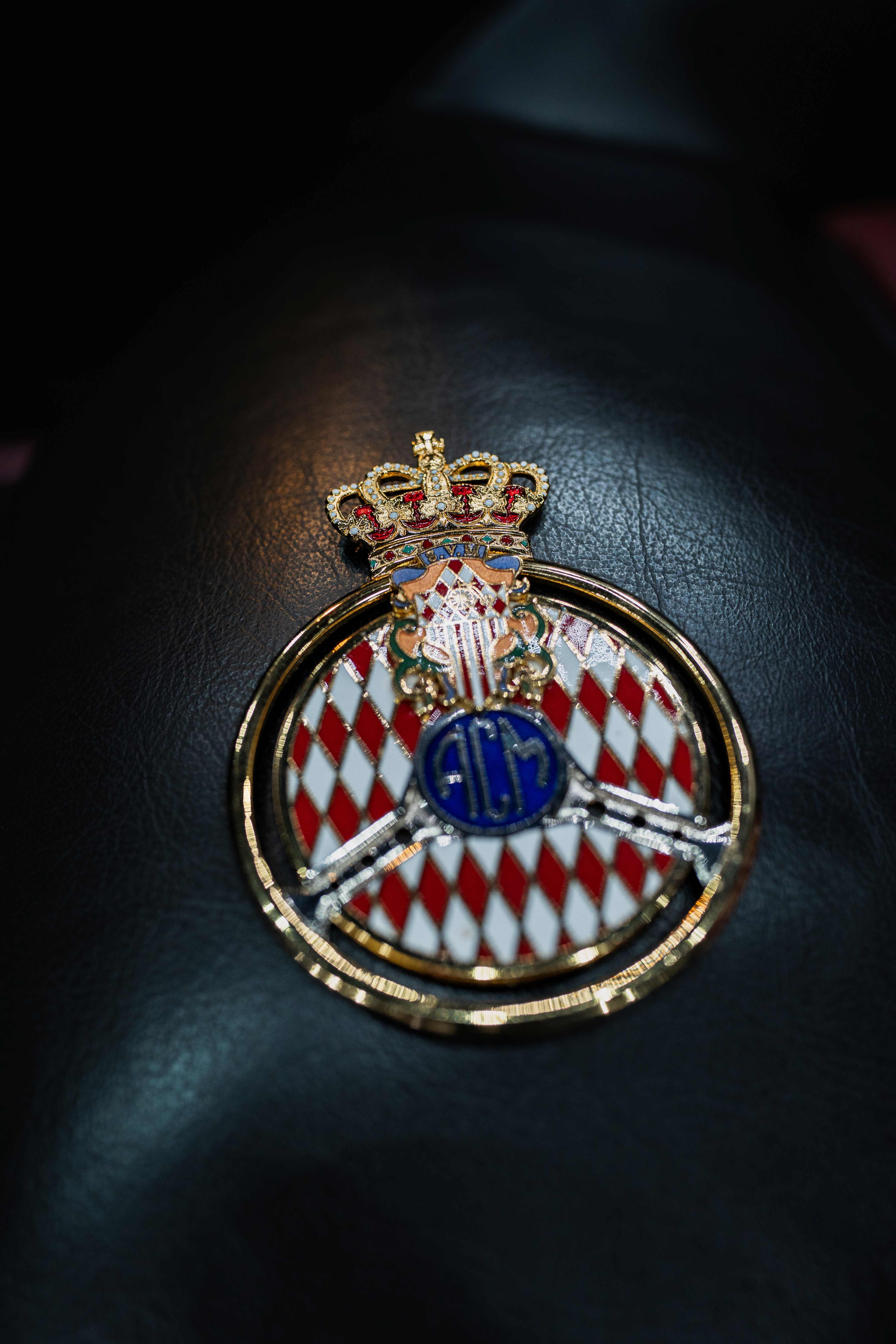 Insigne de concours d'élégance posé sur un cuir noir, détail d'objet automobile rare